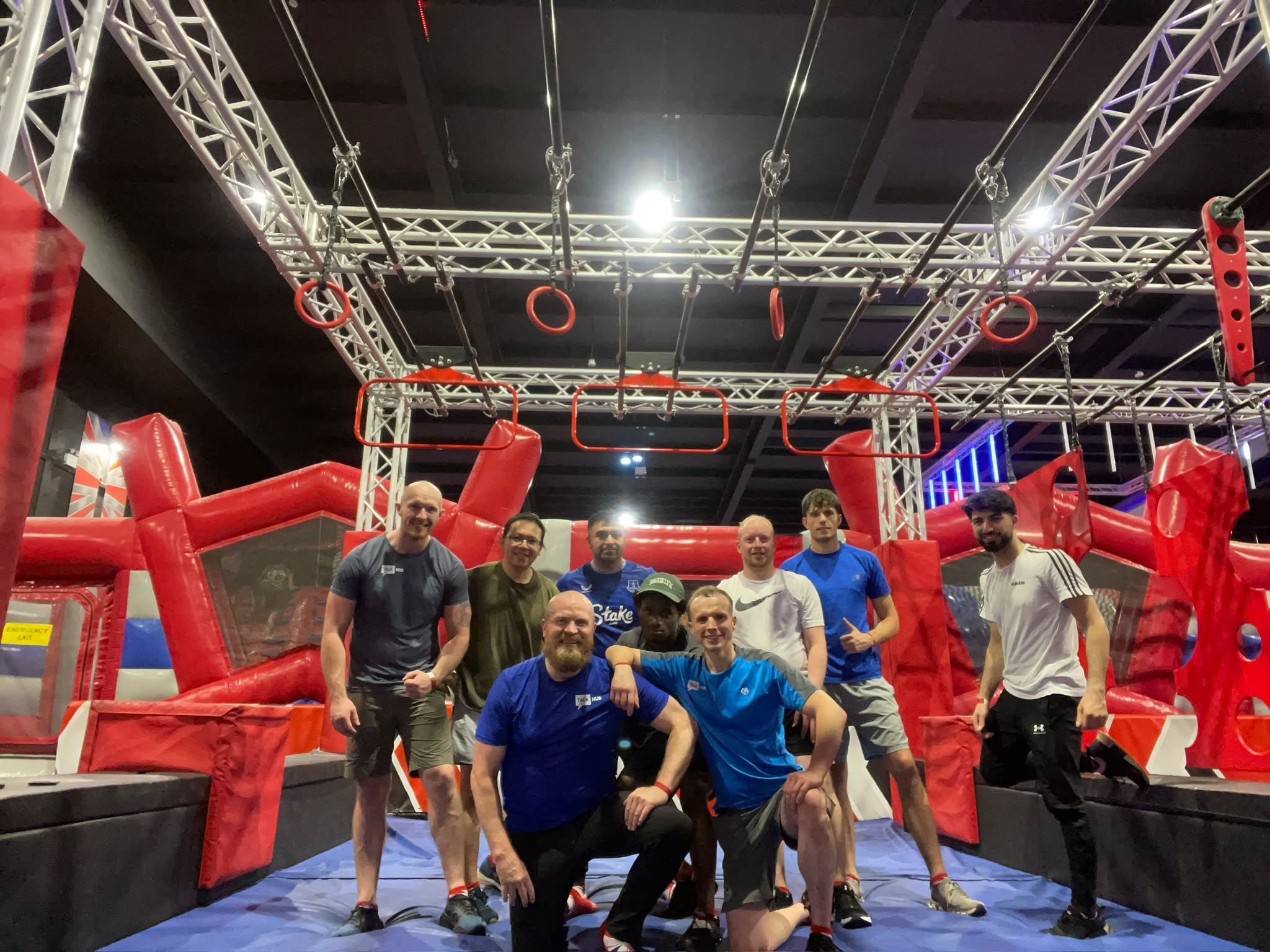TalkHub group posing on an indoor Ninja Warrior obstacle course