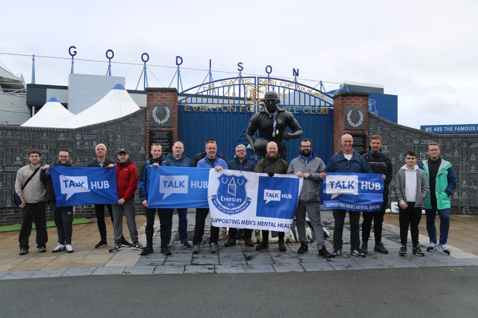 TalkHub walkers outside the Goodison Park gates holding TalkHub and Everton banners