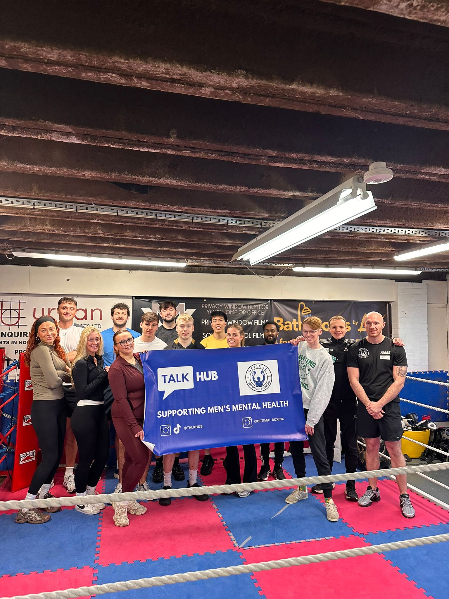 Workshop group standing in the ring at Optimal Boxing holding a TalkHub and Optimal Boxing banner reading Supporting Men’s Mental Health