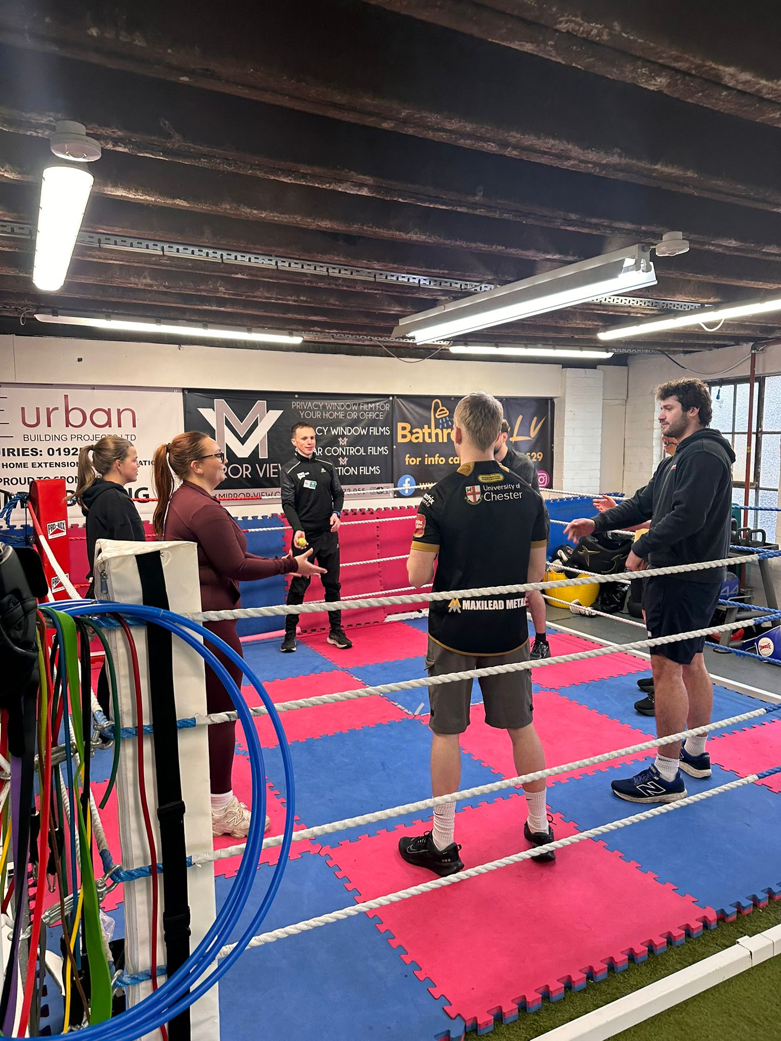 Jay leading a group activity with workshop participants inside the boxing ring at Optimal Boxing